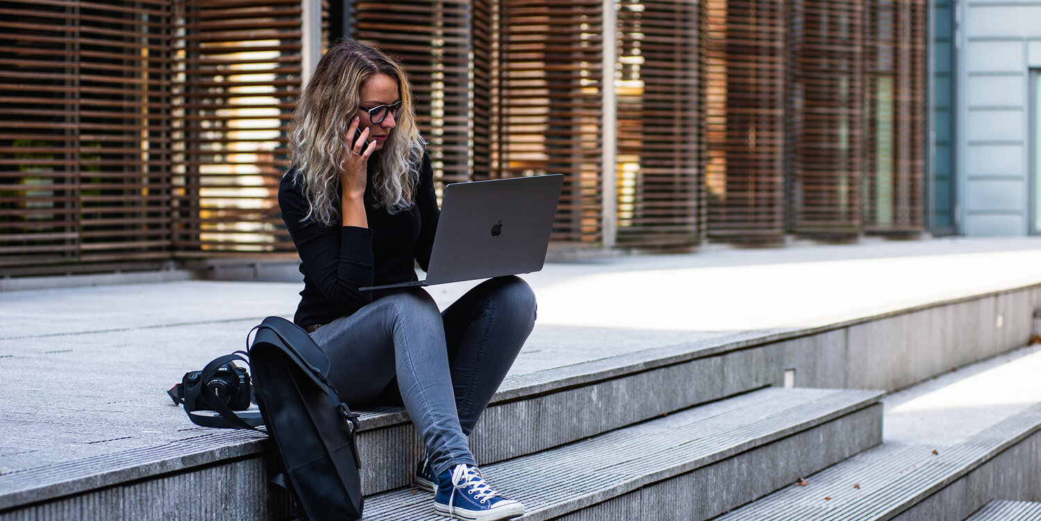 Woman sitting on stairs outside of office talking on cell phone