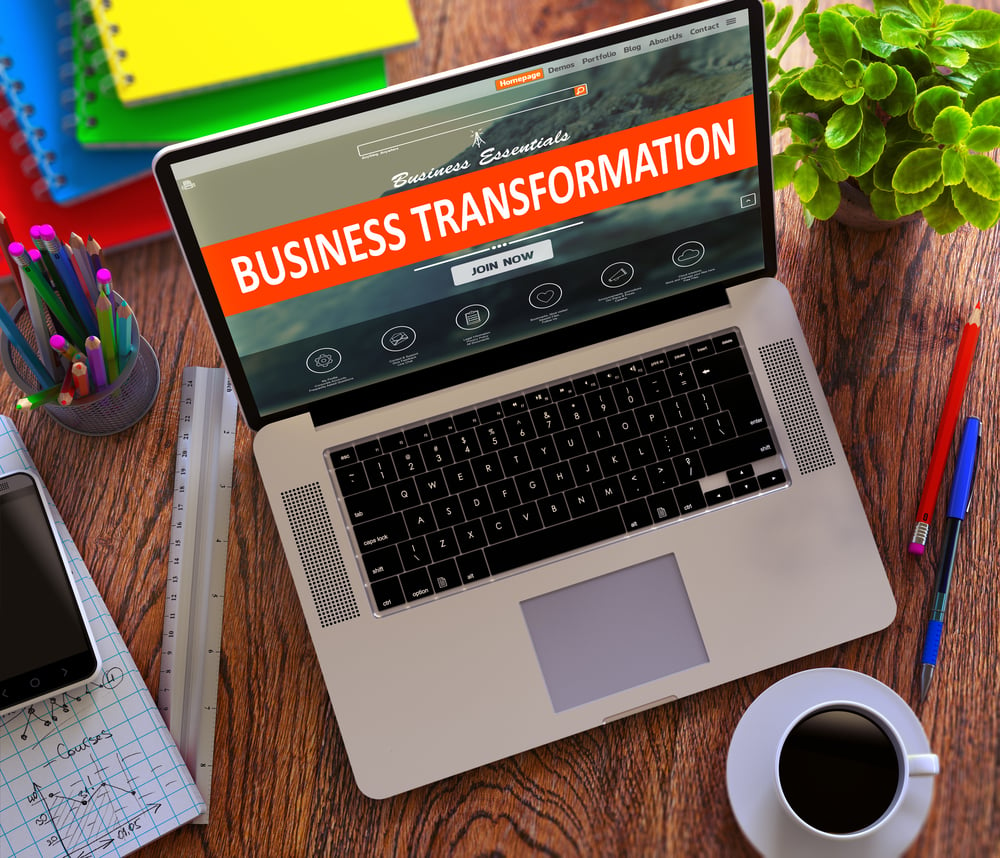 Business Transformation Concept. Modern Laptop and Different Office Supply on Wooden Desktop background.